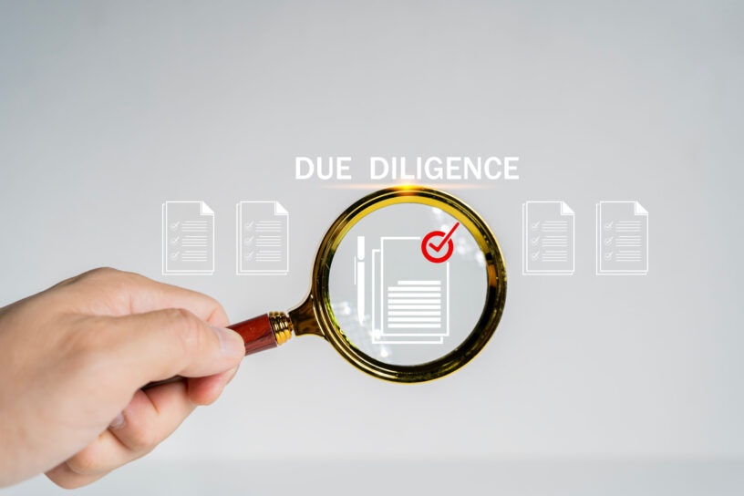 Due diligence concept. Businessman using magnifying glass with due diligence icon on virtual screen for due diligence